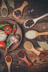 Many different spices and vegetables on a wooden table, aromatic spices and fresh vegetables for cooking, a variety of spices