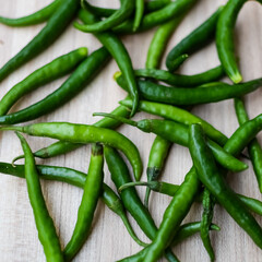 Fresh Green chili pepper on plain wooden table, green essential vegetables for all essential foods, view of unpeeled vegetables with plain background