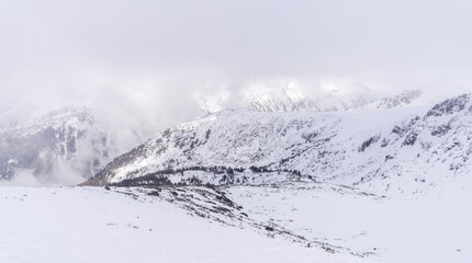 The white snowy peaks of Pirin covered with snow and fog. Snowy weather conditions for winter sports and tourism. Bansko Alpine Ski Resort, Bulgaria.