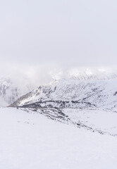 The white snowy peaks of Pirin covered with snow and fog. Snowy weather conditions for winter sports and tourism. Bansko Alpine Ski Resort, Bulgaria.