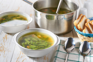 Delicious green bean soup on a white wooden table.