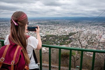 Mujer turista tomando fotos desde el mirador del Cerro San Bernardo, en la ciudad de Salta - obrazy, fototapety, plakaty