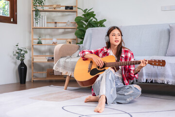 Concept of relaxation with music, Young asian woman wearing headphone and playing acoustic guitar
