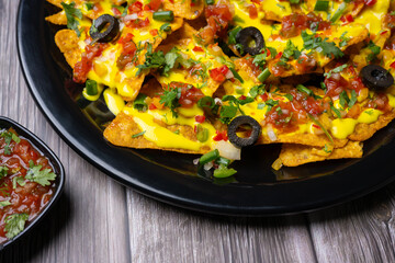 Nachos a Mexican culinary dish consisting of tortilla chips or covered with cheese or cheese sauce, as well as a variety of other toppings and garnishes