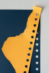 torn orange paper with star border on dark blue paper with embossed texture and star border