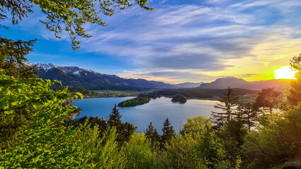 Fototapeta na wymiar Panoramic sunset view on Lake Faak from Taborhoehe in Carinthia, Austria, Europe. Surrounded by high Austrian Alps mountains. Water surface reflecting soft sunlight. Remote alpine landscape in summer