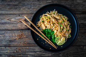 Foto op Canvas Pad Thai with chicken nuggets and rice noodles in peanut and tamarind sauce on wooden table  © Jacek Chabraszewski