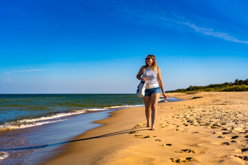 Fototapeta na wymiar Beautiful mid adult woman walking on sunny beach 