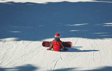 Snowboard sportsmen sitting on snow. Back of snowboarder ready for snowboarding on winter mountain...