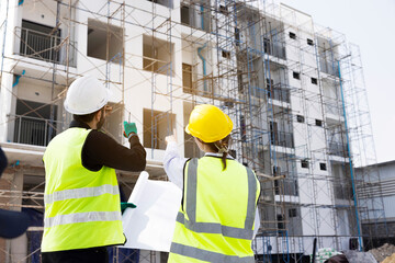 Engineers and Architect Caucasian looking at blueprint of building construction, planning the work in a professional. inspector is looking at steel structure and materials at construction site.