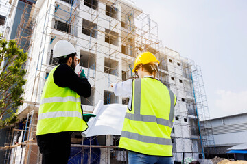 Engineers and Architect Caucasian looking at blueprint of building construction, planning the work in a professional. inspector is looking at steel structure and materials at construction site.