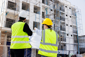 Engineers and Architect Caucasian looking at blueprint of building construction, planning the work in a professional. inspector is looking at steel structure and materials at construction site.