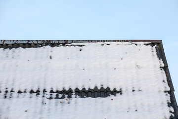 Melting snow on the slate roof of the house, blue sky