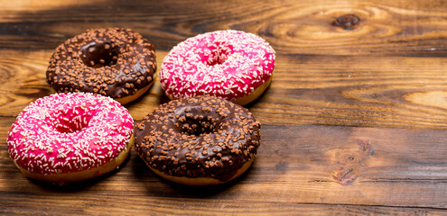 Obraz na płótnie Canvas Chocolate and pink sweet donut on wooden table, breakfast donut