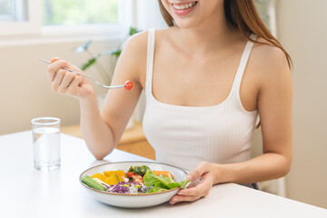 Obraz na płótnie Canvas Diet concept, happy asian young woman hand use a fork to prick tomato, fresh vegetable or green salad, eat nutrition food on table at home, low fat to good body. Girl getting weight loss for healthy.
