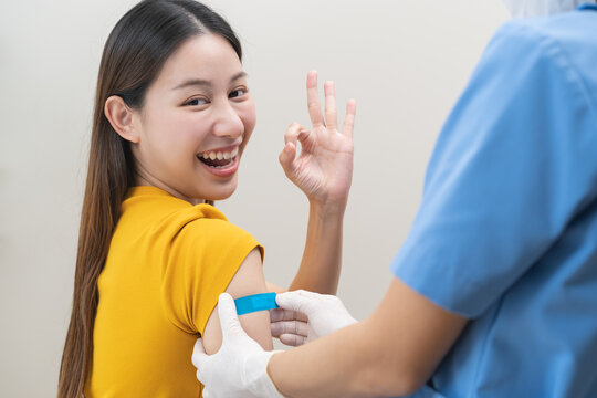 Healthcare of Covid-19, corona anti virus vaccination, happy asian young woman hand showing ok at bandage, plaster on arm, getting vaccine immunity giving injection influenza to protection pandemic.