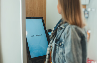 Woman uses a self-service terminal in a store.