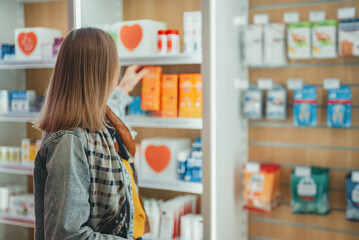 Woman chooses medicine at a pharmacy.