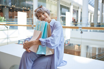 Happy satisfied senior woman holding lots of shopping bags with purchases