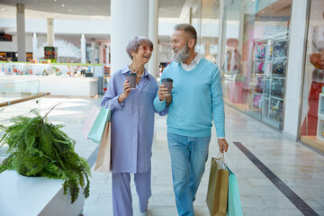 Happy elderly couple in shopping mall going for Black Friday sales