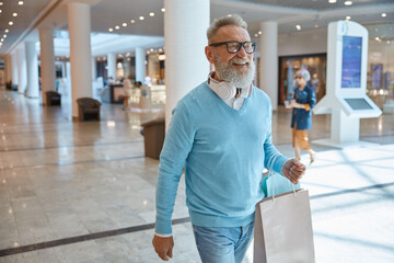 Handsome elegant elderly man with bags in shopping mall