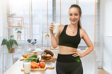 Attractive fitness  caucasian woman finishing workout and drinking protein milk shake vitamins after training at home. Bodybuilding. Healthy lifestyle.