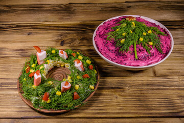 New year salad herring under fur coat (shuba) and festive salad in shape of Christmas wreath on a rustic wooden table. Christmas and new year celebration