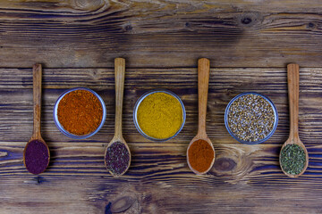 Spoons and bowls with oriental spices on a wooden table. Top view