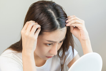Damaged Hair, face serious asian young woman worry looking at scalp in mirror, hand in break into...