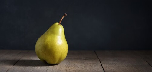  a pear sitting on a wooden table in front of a dark background with a small stick sticking out of it.