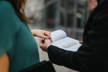 Close up photo of two business people discussing graph charts or growth on a paper.