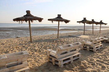 Einsame Liegen und Sonnenschirme am Strand von Cuxhaven an der Nordsee am frühen Morgen