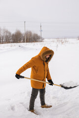 A man cleans and clears the snow in front of the house on frosty day. Cleaning the street from snow...