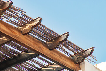 Vigas de madera de un alero en una casa de playa. Primer plano del detalle de la construcción con cañas. Las Negras, Almería, España.