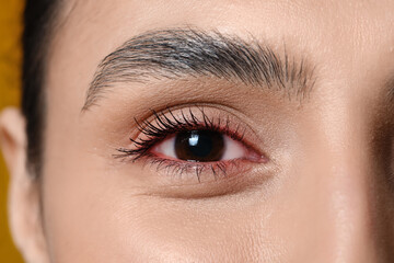 Woman with brown eyes on yellow background, closeup