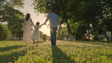 Happy family, kid, runs towards sun, holding hands in city park at sunset. Childhood future, family...