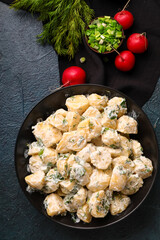 Bowl of tasty Potato Salad with greens on dark background