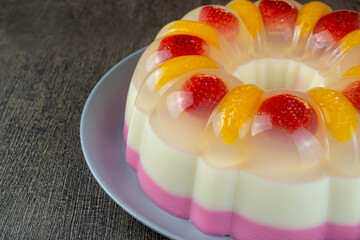 puding lapis or layer pudding with orange and strawberry slices served on a plate at the dark...