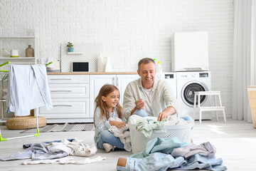Mature man with his little granddaughter and dirty clothes in laundry room - obrazy, fototapety, plakaty