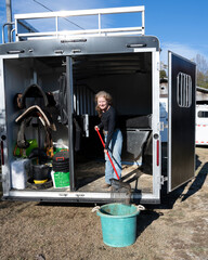 A woman cleaning her horse trailer