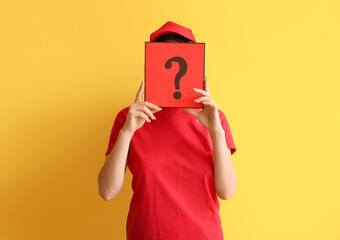 Young woman holding paper sheet with question mark on yellow background