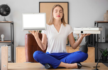 Young businesswoman with laptop and folders meditating on table in office