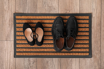 Doormat with shoes on floor, top view