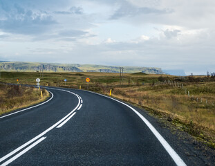 Highway road and mountain view during auto trip in Iceland. Spectacular Icelandic landscape with  scenic nature: fjords, fields, clouds, glaciers, waterfalls.