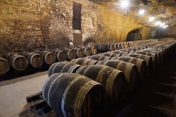 bunch of old wooden wine barrels in limestone cellar in the loire valley, france
