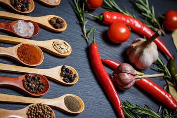 Many different spices and fresh vegetables for cooking on a black background, still life with...