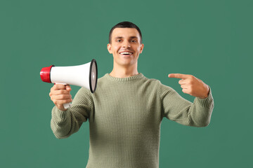 Young man pointing at megaphone on green background