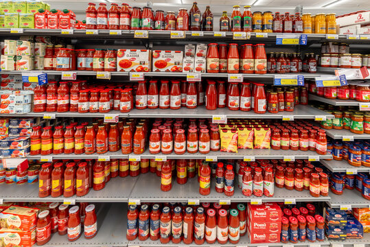Italy - December 15, 2023: Sauce and tomato puree in glass jars and bottles of various types and brands displayed for sale on shelves in Italian supermarket