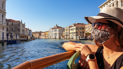 Woman wearing mask on a boat with panoramic view of Grand Canal in city of Venice, Veneto, Italy,...