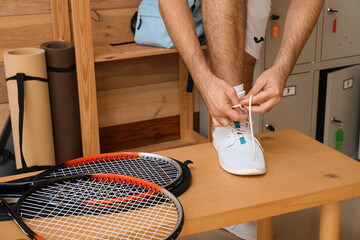 Male tennis player tying shoe laces in locker room, closeup